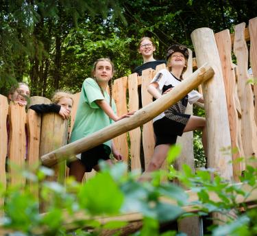 Children climbing on play equipment in the woods